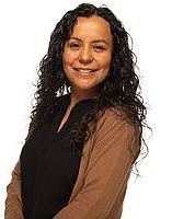 Analizeth Pesqueira stands in front of a white background. She is smiling toward the camera.